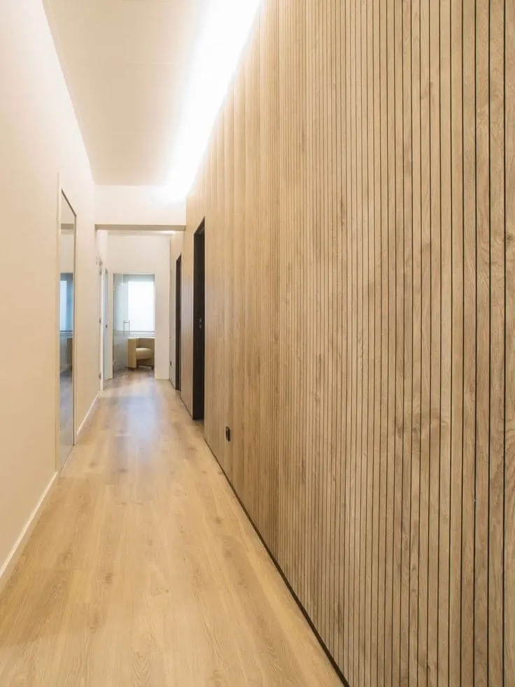 Revestimiento de madera en pasillo moderno con diseño de líneas verticales.