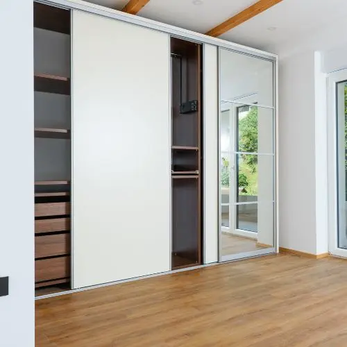 Armario con puertas corredizas de color blanco con un espejo en una habitacion de Montevideo.