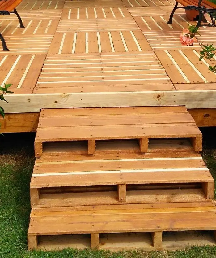 Escalera de madera rústica que forma parte de un deck exterior diseñado con materiales reciclados.