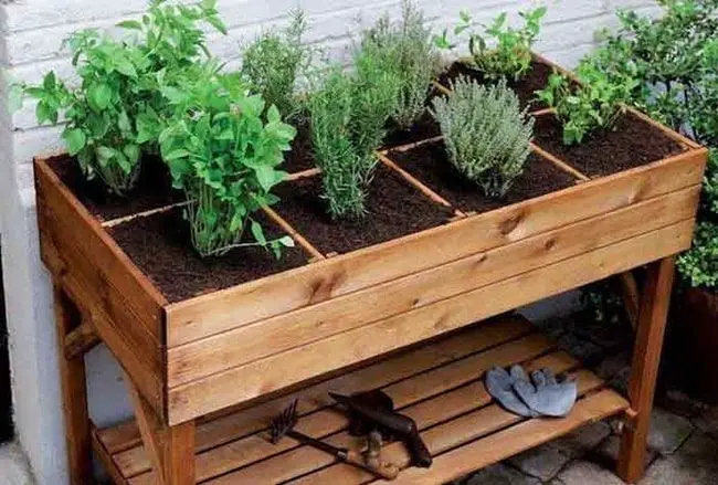 Jardinera de madera con plantas aromáticas frescas como albahaca y romero, ideal para terrazas y balcones.
