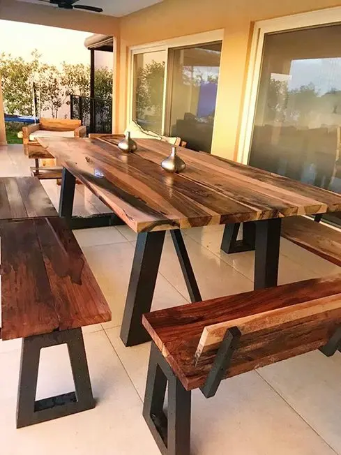 Mesa de madera maciza con base metálica, perfecta para espacios exteriores o interiores con vista panorámica.