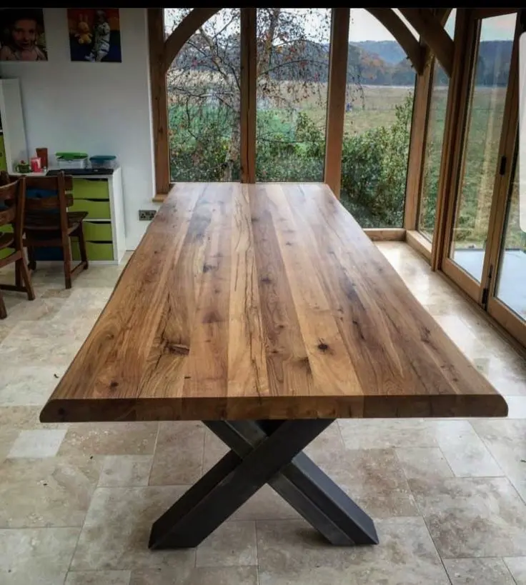 Mesa rústica de madera con bancos, ideal para exteriores, ubicada en una terraza con diseño funcional y moderno