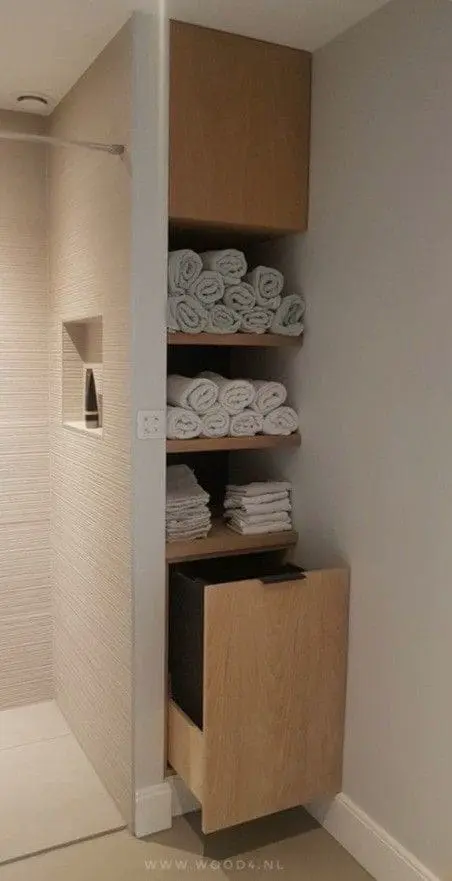 Armario empotrado de madera en baño moderno, con estantes abiertos para organizar toallas y artículos de baño