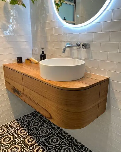 Vanitory de madera con diseño curvo y lavabo redondo, combinando elegancia y funcionalidad en un baño moderno
