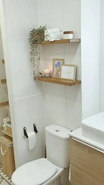 Repisas de madera sobre el inodoro en un baño pequeño, ideales para optimizar el espacio y organizar toallas y artículos de tocador