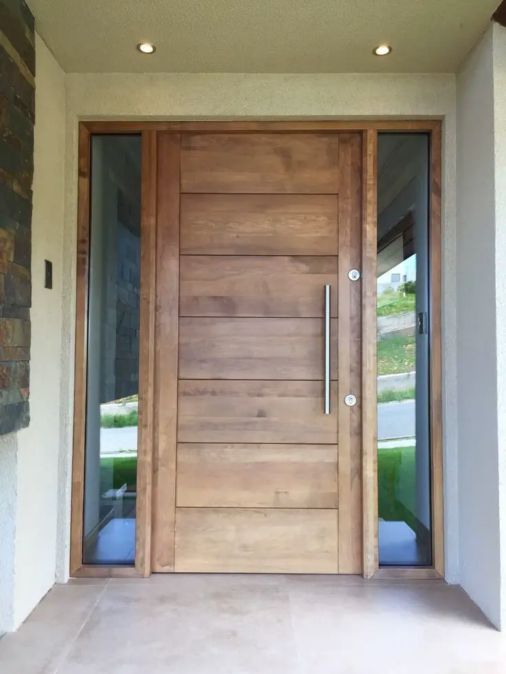 Puerta de entrada de madera rústica con diseño robusto y tirador vertical negro, combinada con marcos modernos de vidrio y estructura metálica