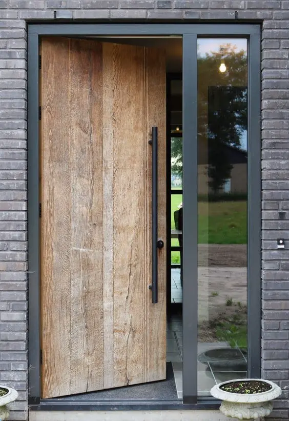 Puerta principal de madera con paneles horizontales y tirador metálico, flanqueada por vidrios laterales que aportan luz y estilo contemporáneo
